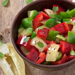 Klein geschnittes Gemüse in einer Schüssel, Messer und Paprika daneben