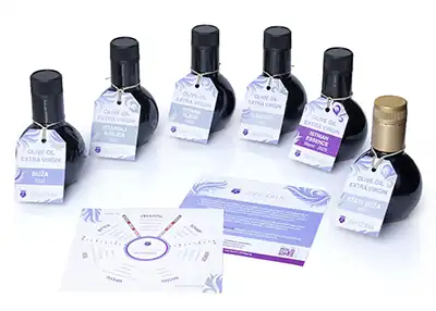 Sechs Flaschen natives Olivenöl extra in verschiedenen Größen und Etiketten, begleitet von einer Informationskarte über die Produkte.